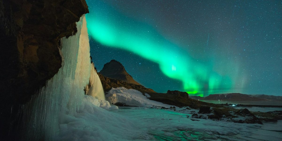 Stunning view of the Northern Lights over Kirkjufell mountain and frozen waterfall in Iceland. Perfect for nature lovers.